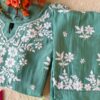 Folded angle view of the pastel sea green muslin chikankari kurta set with elegant embroidery details.